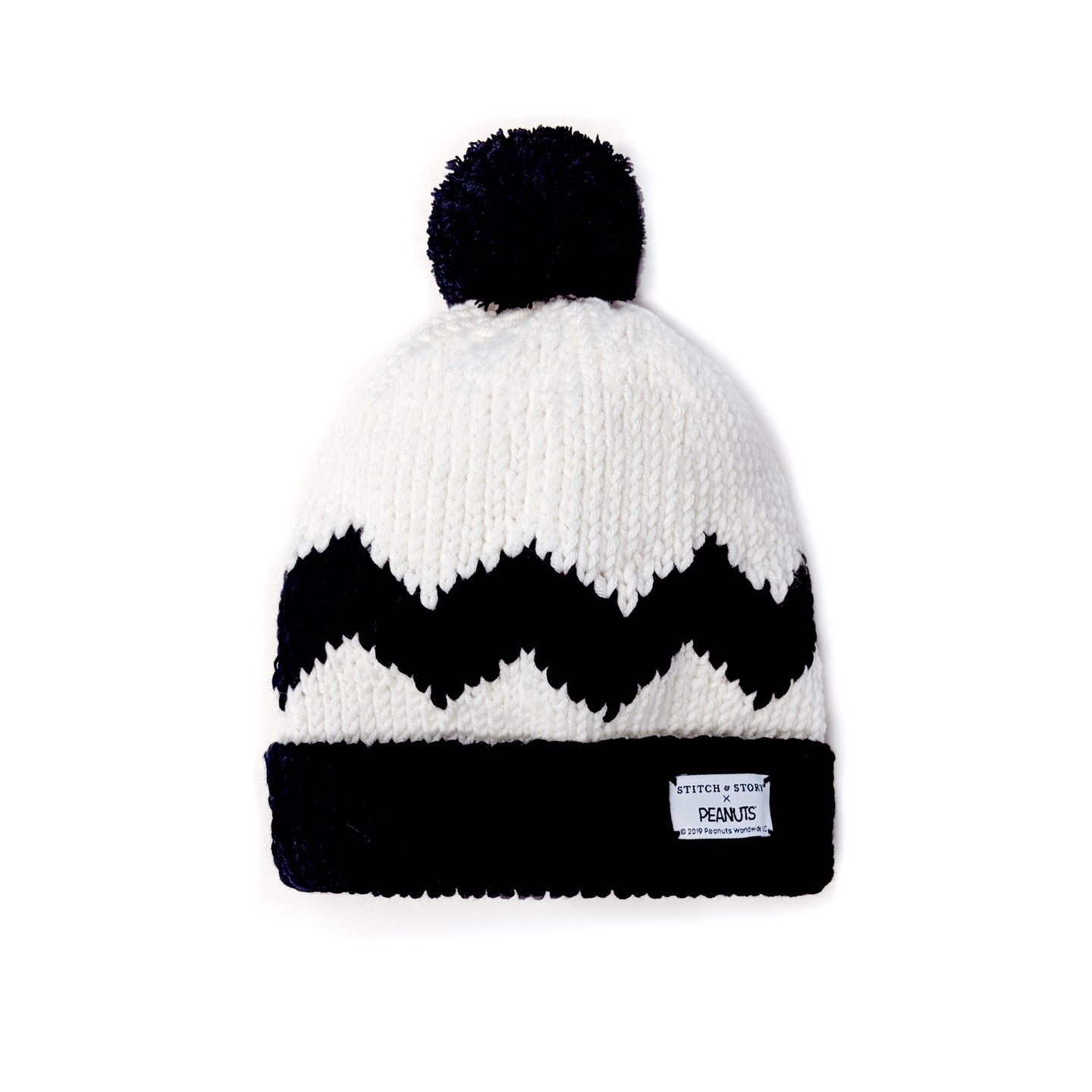A top down photo showing the black and white Stitch & Story's Peanut Charlie Brown beanie, with a Peanuts woven label hand sewn to the front of the black knitting beanie brim.