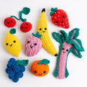 8 fruit crochet amigurumi toys are laid out on a white background with all their smiling faces looking at the camera.