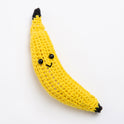 A fun, long banana toy made with Stitch & Story Cotton One in Daisy. yellow has a joyful smiley faces, with an Obsidian black top and bottom mark, on a white background