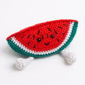A watermelon toy made with Stitch & Story Cotton One in Red Apple and Forest Green has a joyful smiley face, and a pair of dangly feet in Paper White, on a white background