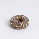 an overhead photo showing the ring sprinkle doughnut crocheted with grey, and decorated with strands of pink, yellow and white in Stitch & Story's Cotton One.