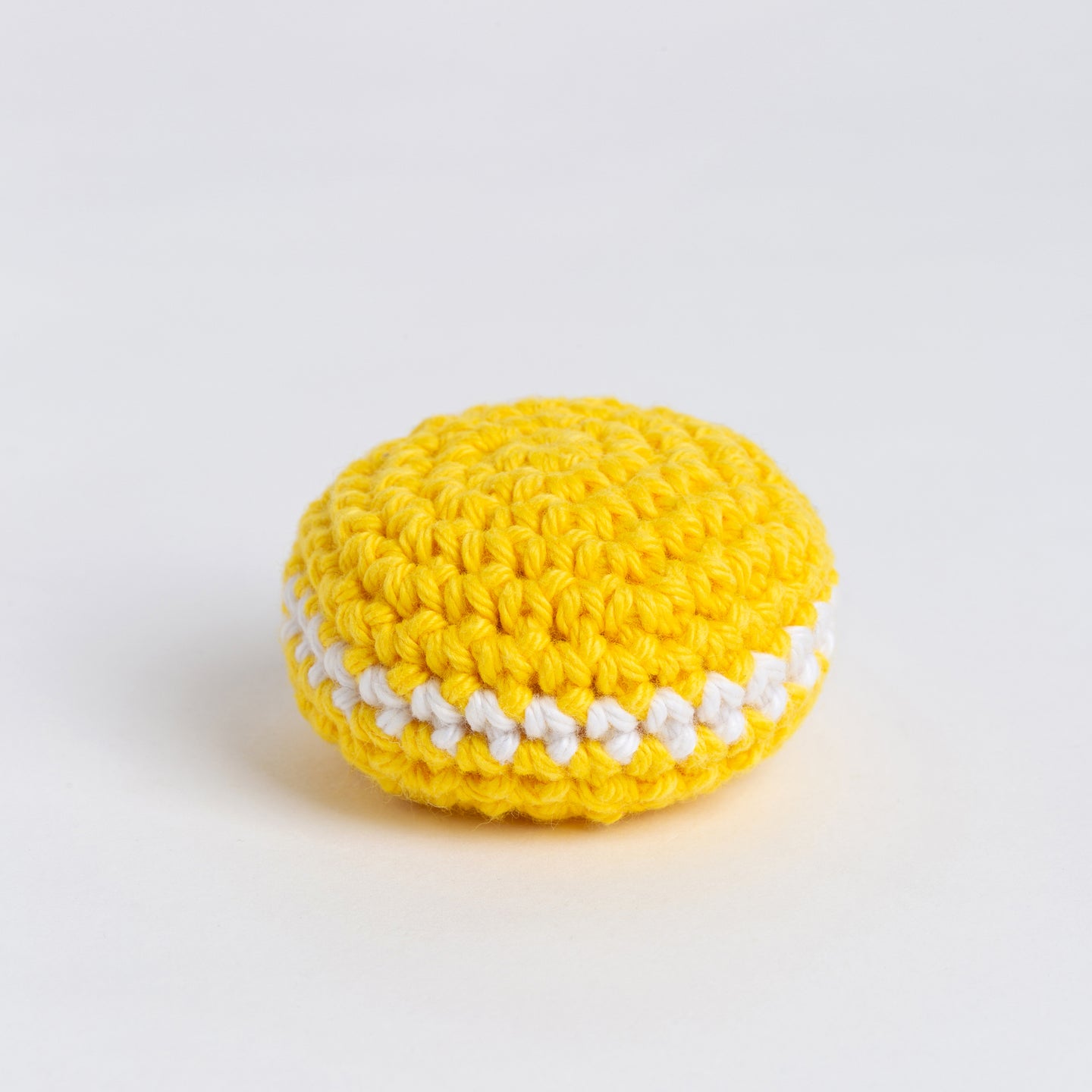 A front on photo showing the crochet lemon macaroon, made with yellow and white Stitch & Story Cotton One yarn.