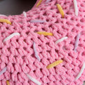 A close up of the pink doughnut sprinkled with Yellow, lilac and white lines, crocheted in Stitch & Story's Roly Poly Plush.