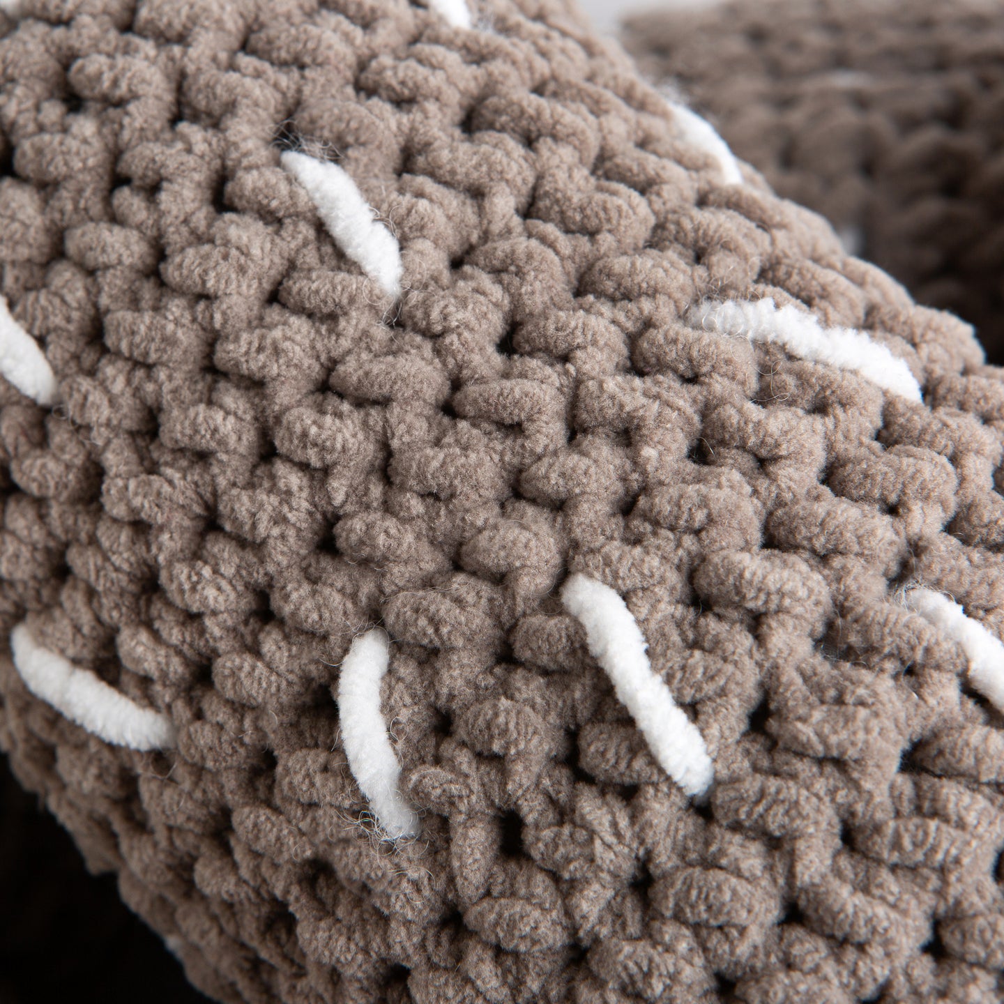 Close up to show the crochet texture of the plush giant light grey pretzel cushion made with Stitch & Story's Roly Poly Plush.