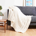 Stitch & Story's soft Lofty Throw knitted in 100% Merino wool Chunky wool in Ivory White on a sofa.