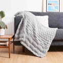 Stitch & Story's soft Lofty Throw knitted in 100% Merino wool Chunky wool in Stormy Grey on a sofa.
