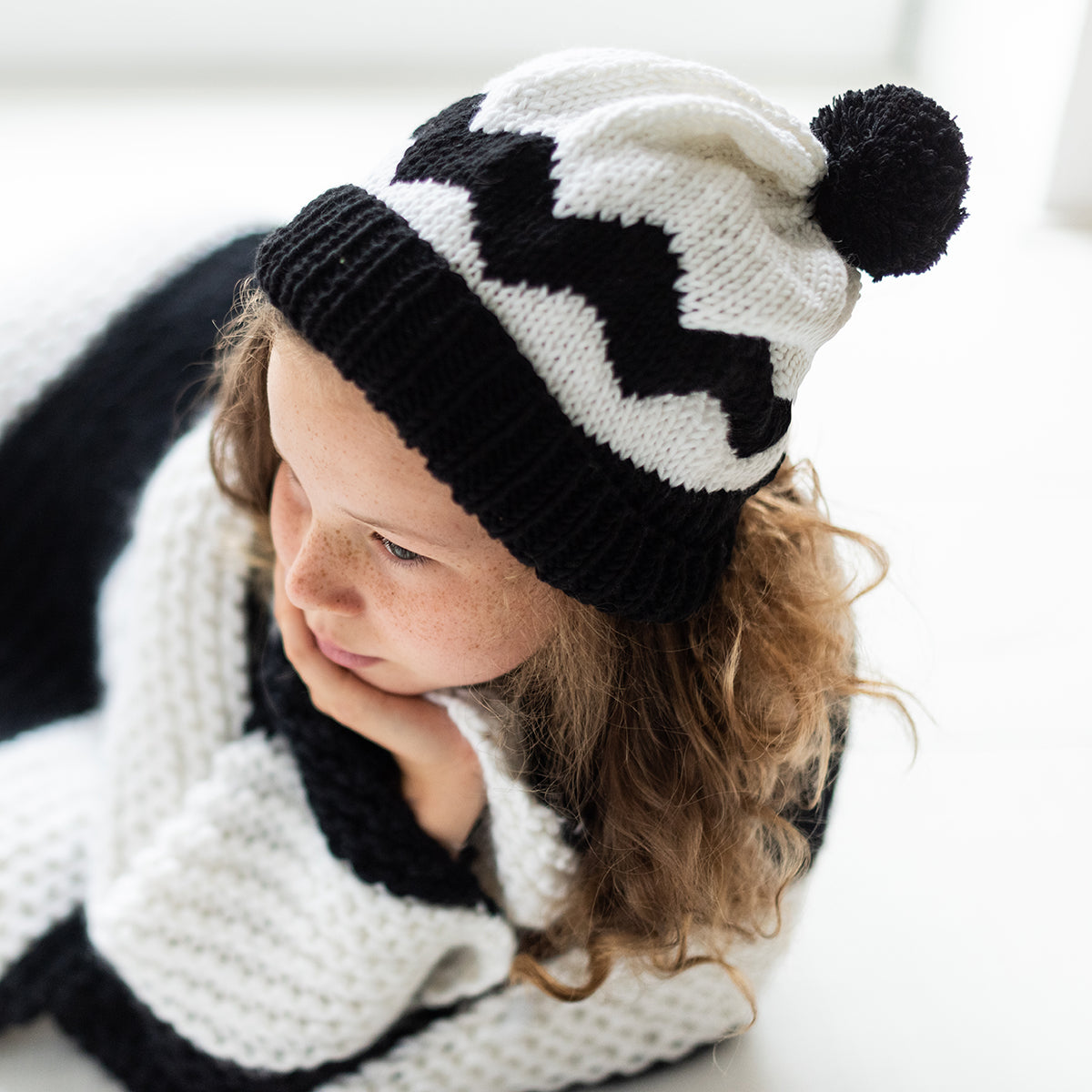 a photo showing a young girl wearing the black and white charlie brown beanie, in a slouchy, relaxed style.