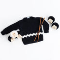 Photo of the Charlie Brown kid sweater, knitted from the knitting kit by Stitch & Story. The long-sleeve sweater is in Black with a graphic White chevron detail across the bottom of the sweater. 