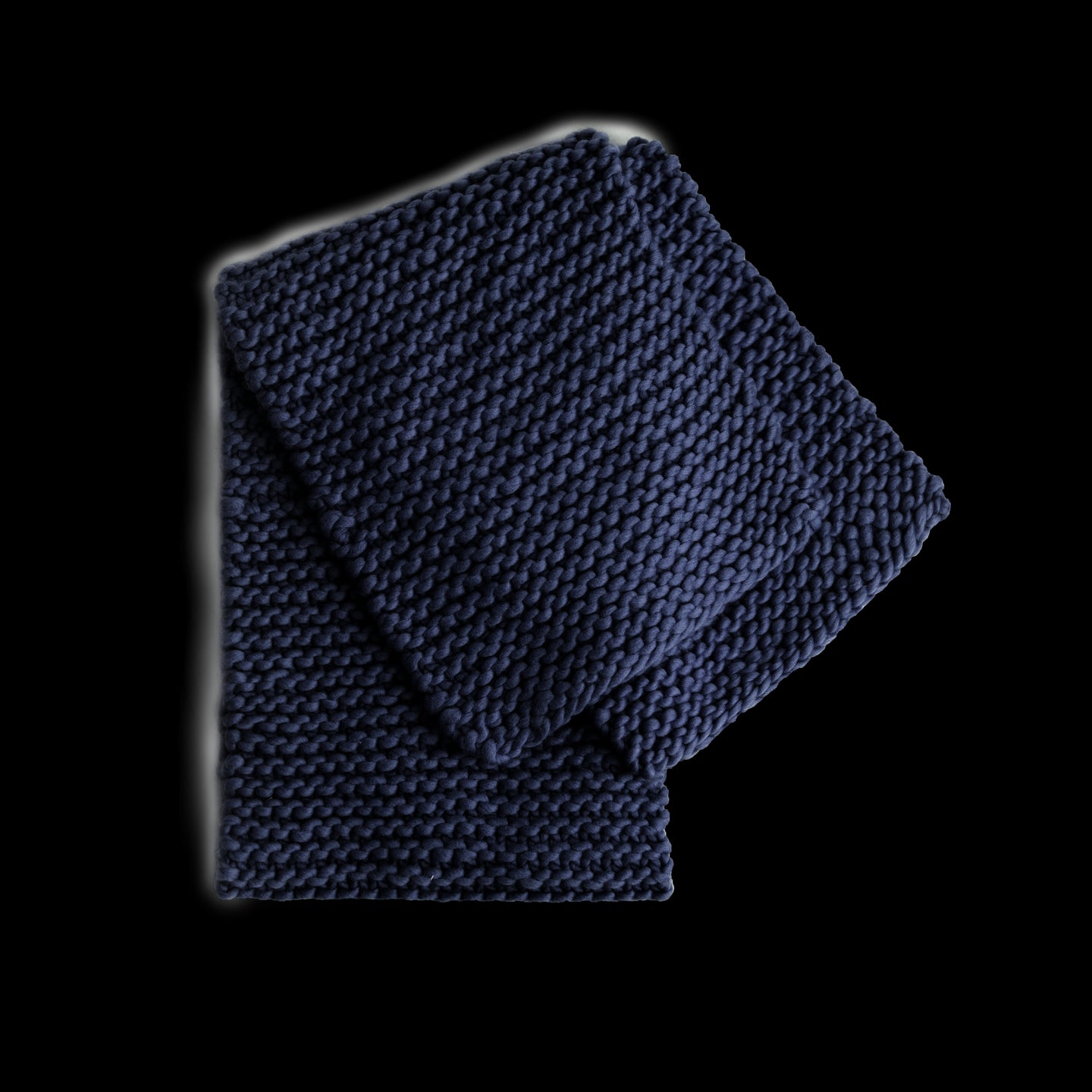 A folded Grazier Scarf in Midnight Blue, knitted from Stitch & Story's Grazier scarf beginner knitting kit.