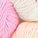 100% merino wool, Stitch & Story's Lil' Merino yarn in colour group, showing a close up of Natural White, Peach Pink and Doe Pink