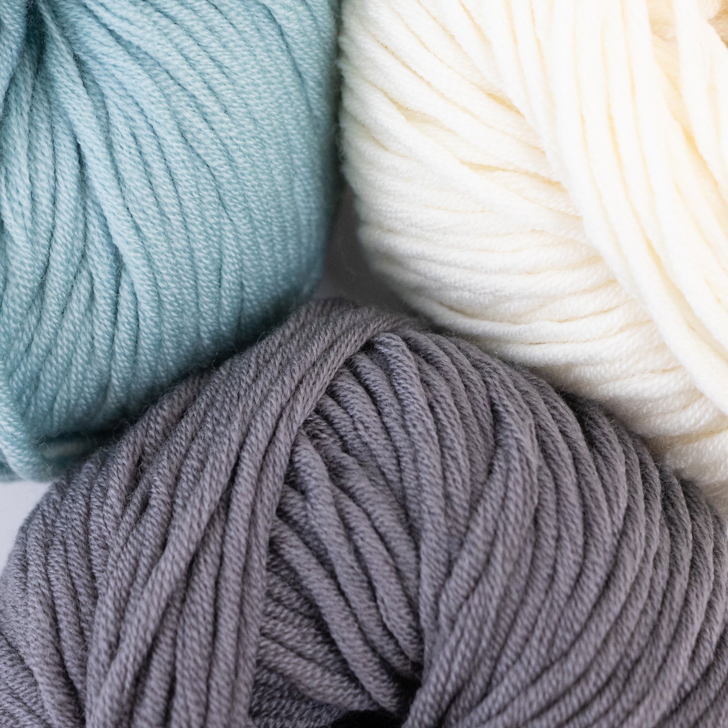 100% merino wool, Stitch & Story's Lil' Merino yarn in colour group, showing a close up of soft Teal, Bright White and Pebble Grey