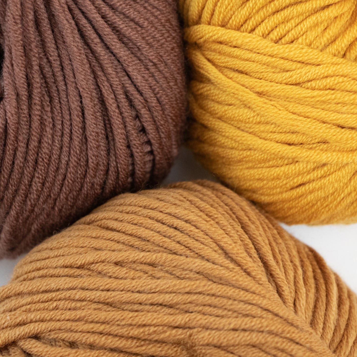 100% merino wool, Stitch & Story's Lil' Merino yarn in colour group, showing a close up of Chestnut Brown, Sand Gold and tan