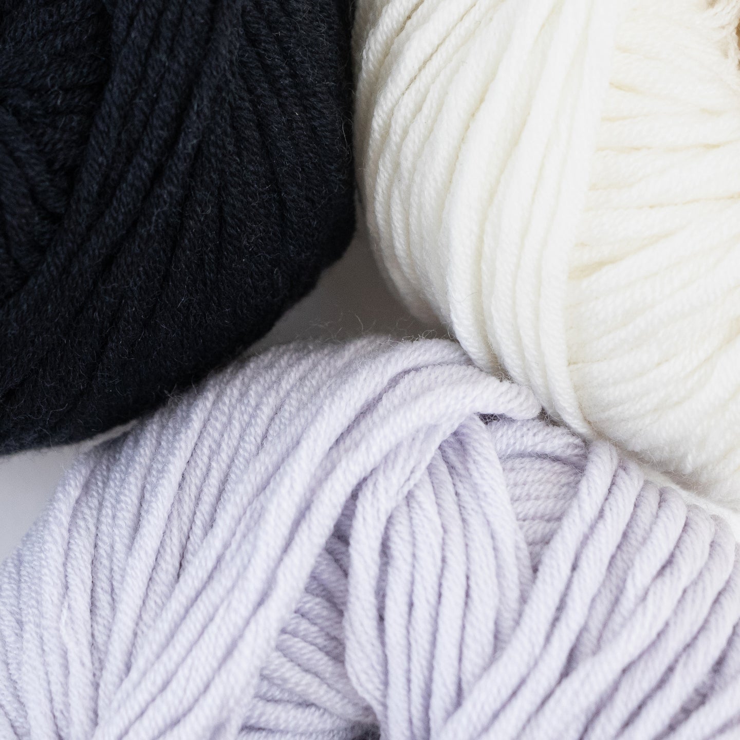 100% merino wool, Stitch & Story's Lil' Merino yarn in colour group, showing a close up of Comic Black, dove grey and bright white