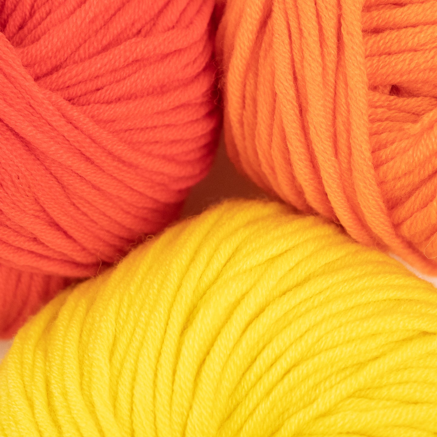 100% merino wool, Stitch & Story's Lil' Merino yarn in colour group, showing a close up of Tulip Red, Dutch Orange and Sherbet Yellow