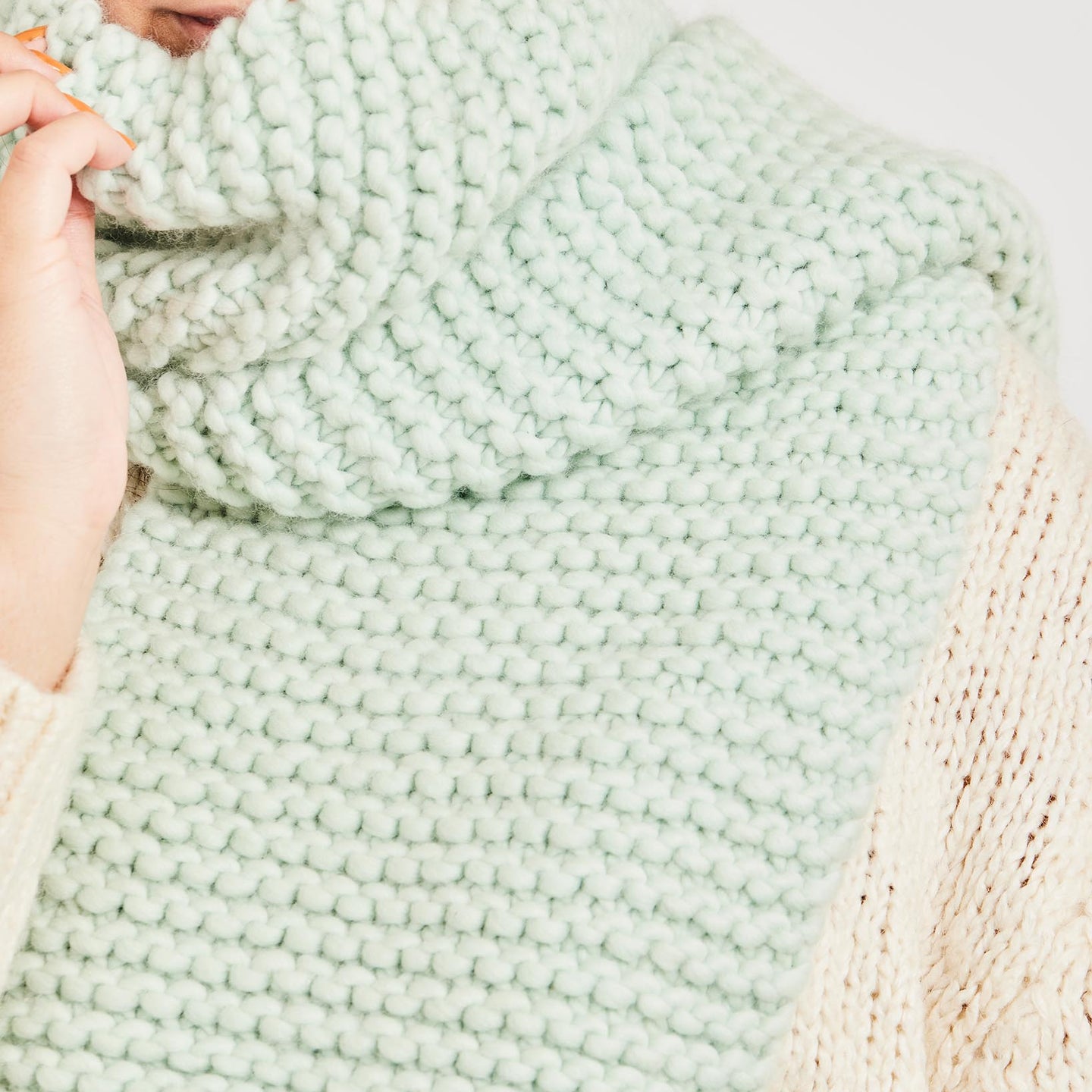 Someone is wrapped up cosily in Stitch & Story's Grazier chunky wool scarf in Iced Mint, knitted from the 100% merino Chunky Wool included in the knitting kit.