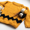 A close up of the women's Charlie Brown sweater in Mustard yellow and star black, showing each stitch detail, knitting with 100% merino wool The Chunky Wool from Stitch & Story.