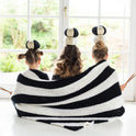 3 girls are playfully balancing balls of Stitch & Story 100% merino wool The Chunky Wool whilst wrapped together in the Snoopy black and white chunky Throw, knitted from the Snoopy Throw knitting Kit.