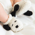 A close up of the Snoopy baby booties, made in this Stitch & Story knitting kit, in 100% Bright White Merino Wool.