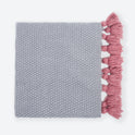 A folded Stormy Grey Chunky Tassel Throw with Dust Pink Tassels.