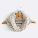 An Ivory White Mateusz Snood is hung on a hanger. This is knitted with the beginner friendly Stitch & Story knitting kit.