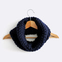 A Midnight Blue Mateusz Snood is hung on a hanger. This is knitted with the beginner friendly Stitch & Story knitting kit.