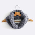 A Stormy grey Mateusz Snood is hung on a hanger. This is knitted with the beginner friendly Stitch & Story knitting kit.